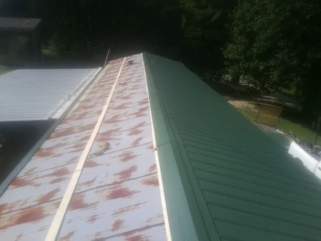 Old rusted panels beside newly installed green metal roofing — Wind Damage Roof Repair by Roofing Brothers in Coudersport